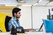 © wavebreak3 - Asian man in early 30s typing on laptop at desk in open-plan office, highlighting blurred telephone