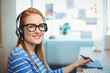 © WavebreakMediaMicro - Woman wearing headphones using graphics tablet at home office desk showing pinned notes, copy space