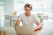 © WavebreakMediaMicro - Man typing on silver laptop at wood table in modern dining area, with yellow flower vase