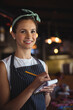 © WavebreakMediaMicro - Female waitress smiling and taking order in casual restaurant, with order pad and yellow pencil