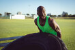 © Wavebreak Media - African American man flipping large tractor tire on grassy field, demonstrating strength training