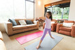 © Wavebreak Media - Child practicing yoga on gray mat in living room, with sofa cushions and sliding glass door