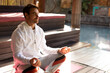 © Wavebreak Media - Young adult male meditating on pink yoga mat at poolside wooden deck with pool water reflections