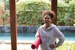 © Wavebreak Media - Woman standing under wooden pergola in backyard beside pool, holding pink yoga mat and laughing