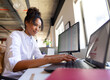© Wavebreak Media - Office professional woman typing on laptop at office desk with external monitor and potted plant