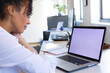 © Wavebreak Media - Woman leaning forward at desk in bright office, using laptop with notebook and pen, copy space