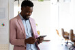 © Wavebreak Media - Mid adult African American man leaning on whiteboard charts in office, tapping tablet, copy space