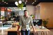 © Wavebreak Media - Mid adult man leaning on wooden desk in open plan office, holding coffee near computer monitor