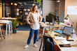 © Wavebreak Media - Female office worker standing hands on hips in open-plan office, with laptops and potted plants