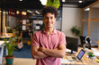 © Wavebreak Media - Young adult man standing with arms crossed in modern open-plan office, with laptops and plants