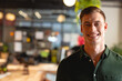 © Wavebreak Media - Man standing and smiling in open-plan office with hanging plant and glass partitions, copy space