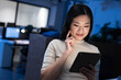 © Wavebreak Media - Asian woman tapping tablet in dimly lit modern open?plan office with computer monitors, copy space
