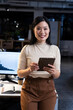 © Wavebreak Media - Asian woman holding tablet and reviewing data in open-plan office, using bar chart monitor