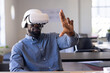 © Wavebreak Media - Young adult African American man using virtual reality headset at open office desk, with papers