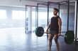 © Wavebreak Media - Young adult male fitness enthusiast lifting barbell on gym floor with green plates, copy space