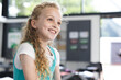 © Wavebreak Media - 8-year-old student sitting at desk and smiling in modern classroom, with papers and backpack