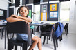 © Wavebreak Media - Girl student leaning on black chair back in classroom with blue backpack on desk, copy space