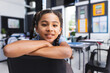 © Wavebreak Media - Girl child leaning on chair back among student desks in classroom, showing posters and monitor