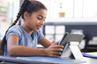 © Wavebreak Media - Multiracial girl student sitting at desk in bright classroom, using tablet on stand, copy space