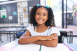 © Wavebreak Media - Young girl sitting at desk in modern classroom, writing in open notebook with green pencil