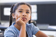 © Wavebreak Media - Multiracial schoolgirl sitting at school desk in classroom, resting chin on hand and gazing upward