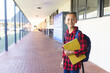 © Wavebreak Media - 10-year-old boy standing in school hall, carrying yellow notebooks and blue backpack, copy space