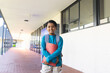 © Wavebreak Media - Boy student standing in covered school corridor smiling with red binder and striped backpack