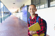 © Wavebreak Media - 10-year-old boy standing in covered school corridor, holding yellow binder and smiling, copy space
