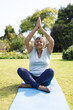 © Wavebreak Media - Diverse senior female practicing yoga on blue mat in garden, with sunlit shrubs and bright sky