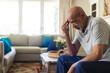 © Wavebreak Media - Senior African American man sitting in living room, holding forehead near wicker basket, copy space