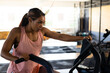 © Wavebreak Media - Diverse woman pedaling on stationary air bike in gym with rubber mats, cardio machines, copy space