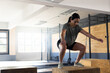 © Wavebreak Media - Woman performing box jump squat on plyometric box in industrial gym with metal rig, copy space