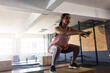 © Wavebreak Media - Woman performing box squat in well-lit CrossFit gym, with wooden box, barbells and industrial fan