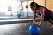 © Wavebreak Media - Young adult multiracial woman performing push-up on blue ball in gym, showing power, copy space