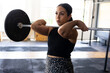 © Wavebreak Media - Mid-adult woman holding loaded barbell at collarbone in CrossFit gym, with rubber flooring