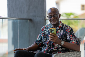 Senior African citizen uses his smartphone for social media and video calls his family outside the country.