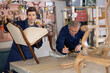 © JackF - Skilled old middle-aged male furniture repair specialists restoring old-fashioned chair mirror frame in workshop