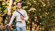 © Prostock-studio - Modern lifestyle and ecological transport. Happy hipster in glasses holding coffee and walking with bike in park, copy space