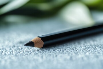 Fototapete - Black pencil resting on fabric with soft green background highlighting its sharp tip and textured surface