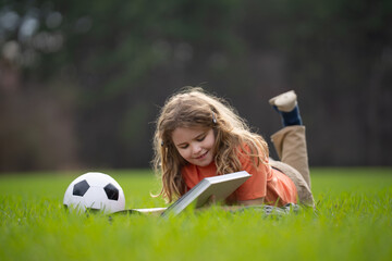Aufkleber - Child reading a book in the grass. Kid enjoying a book story outdoors. Child studying with book in the meadow on a sunny day. Learning in nature. Schoolboy reading book in the park. Outdoor learning.