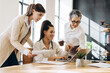© Maria Vitkovska - Businesswomen collaborating on laptop in modern office