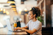 © Dusan Petkovic - Profile view of interracial freelancer sitting in coffee shop and typing report on laptop.
