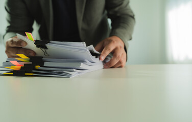 Poster - Stacks of paper files and checking document businessman checks financial documents on his laptop, managing corporate reports and legal paperwork at his office desk.