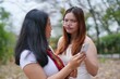© Charlie's - Asian women friends talking and using smart phone on park.