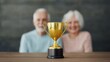 © Slowlifetrader - Rewarding the final stage of life or retirement to ensure a joyful life. A golden trophy with a blurred background of an elderly man and woman smiling.
