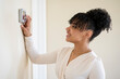 © Cavan - Smiling woman adjusts digital thermostat on wall