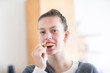 © Cavan - Young woman eating a cookie at home