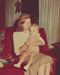 © Stock'd  - stylish mother holding child in lounge at christmas, vintage color photo, old and faded 1960s mom