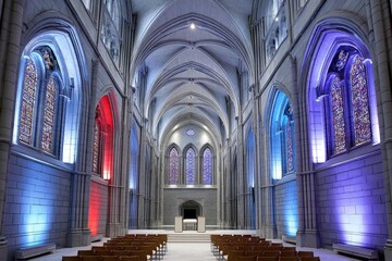 Poster - A gothic cathedral with stained glass windows tinted red white and blue casting moody light