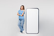 © ViDi Studio - Full body young woman wears blue t-shirt casual clothes point index finger on big huge blank screen mobile cell phone smartphone with area isolated on plain white color background. Lifestyle concept.